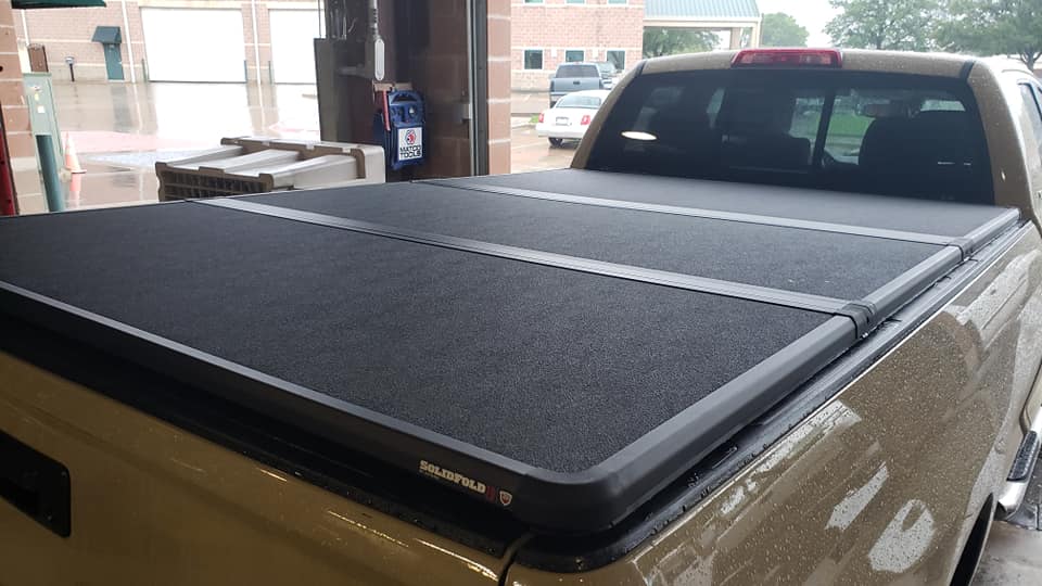 tri-fold bed cover on a beige truck